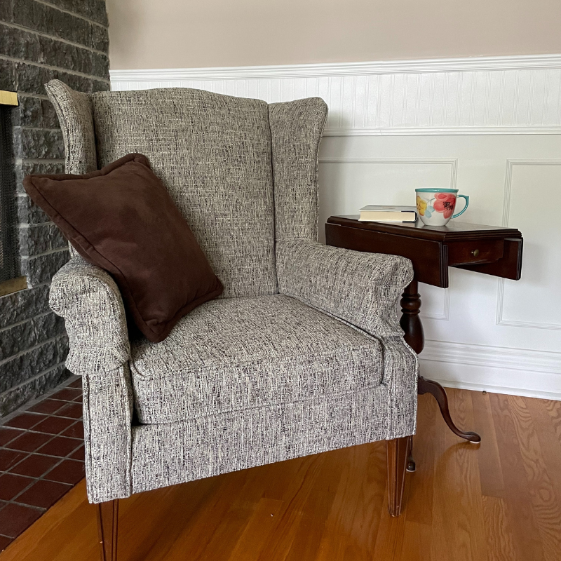 New upholstery of a grey chair in the corner of a living room with custom made pillow