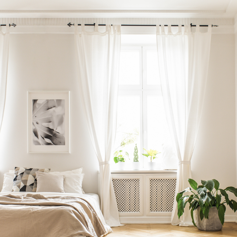 White custom drapery displayed on a sun-filled bedroom window.